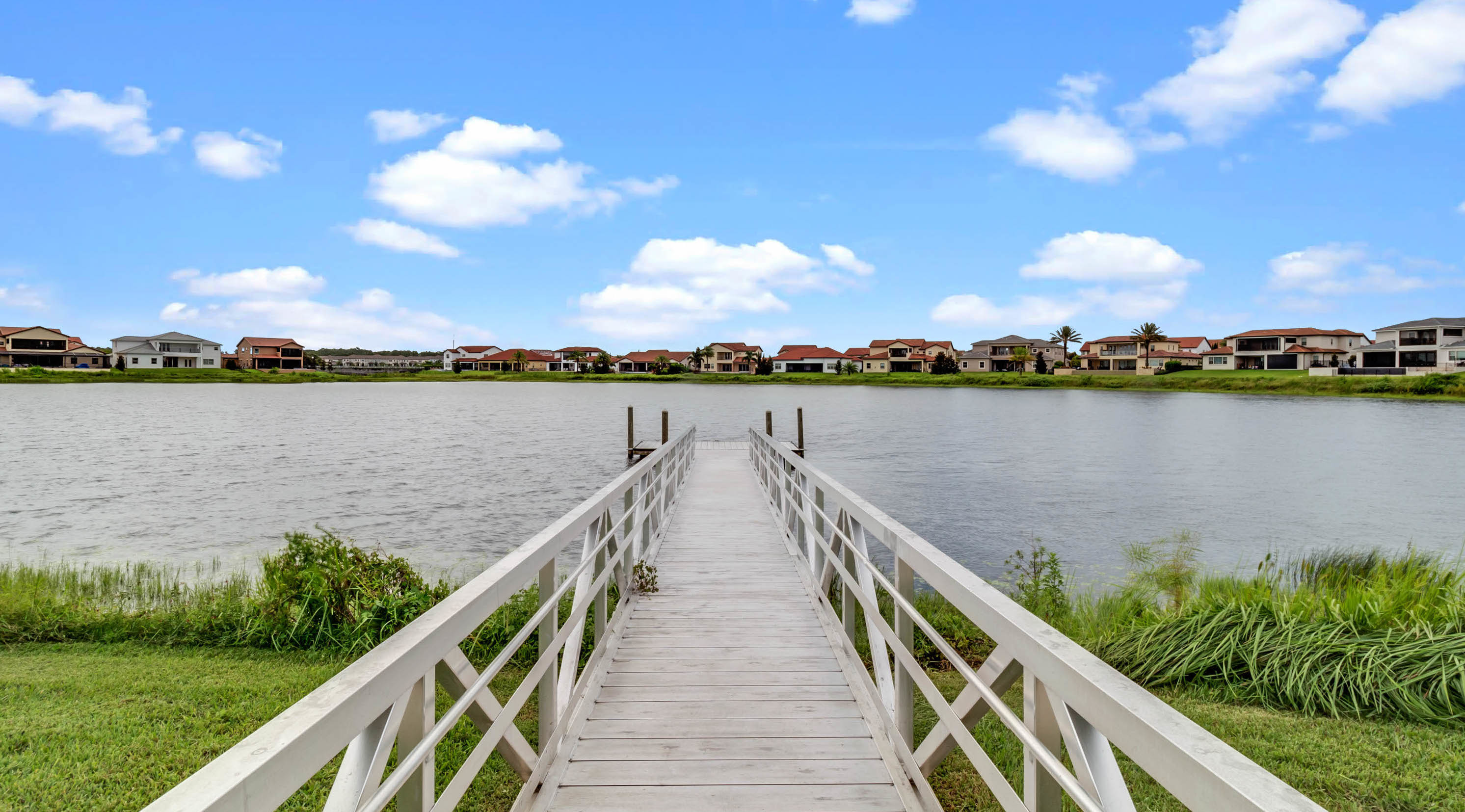 white bridge to lake with homes on horizon line