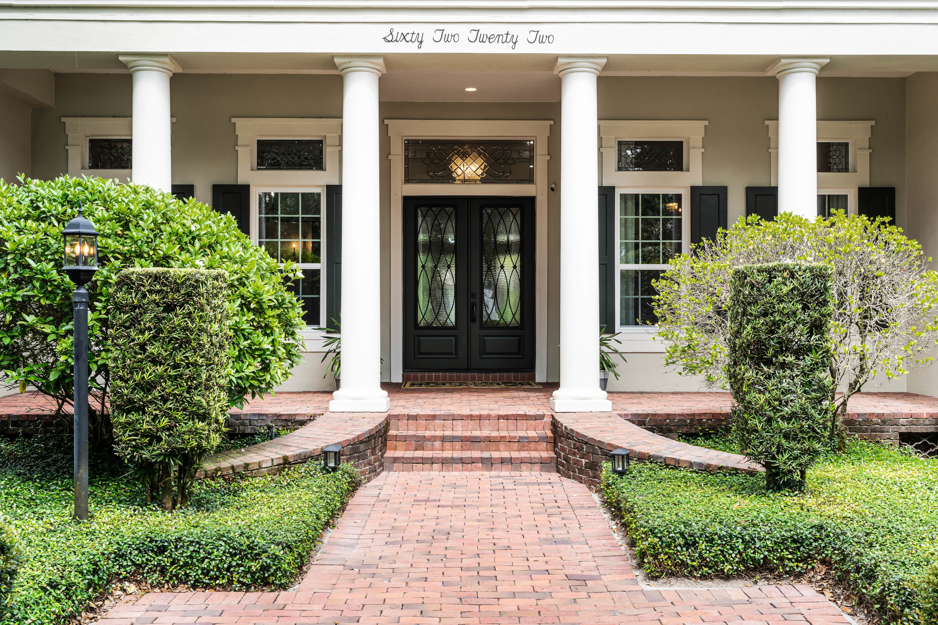 front of home with white columns and red brick pathway