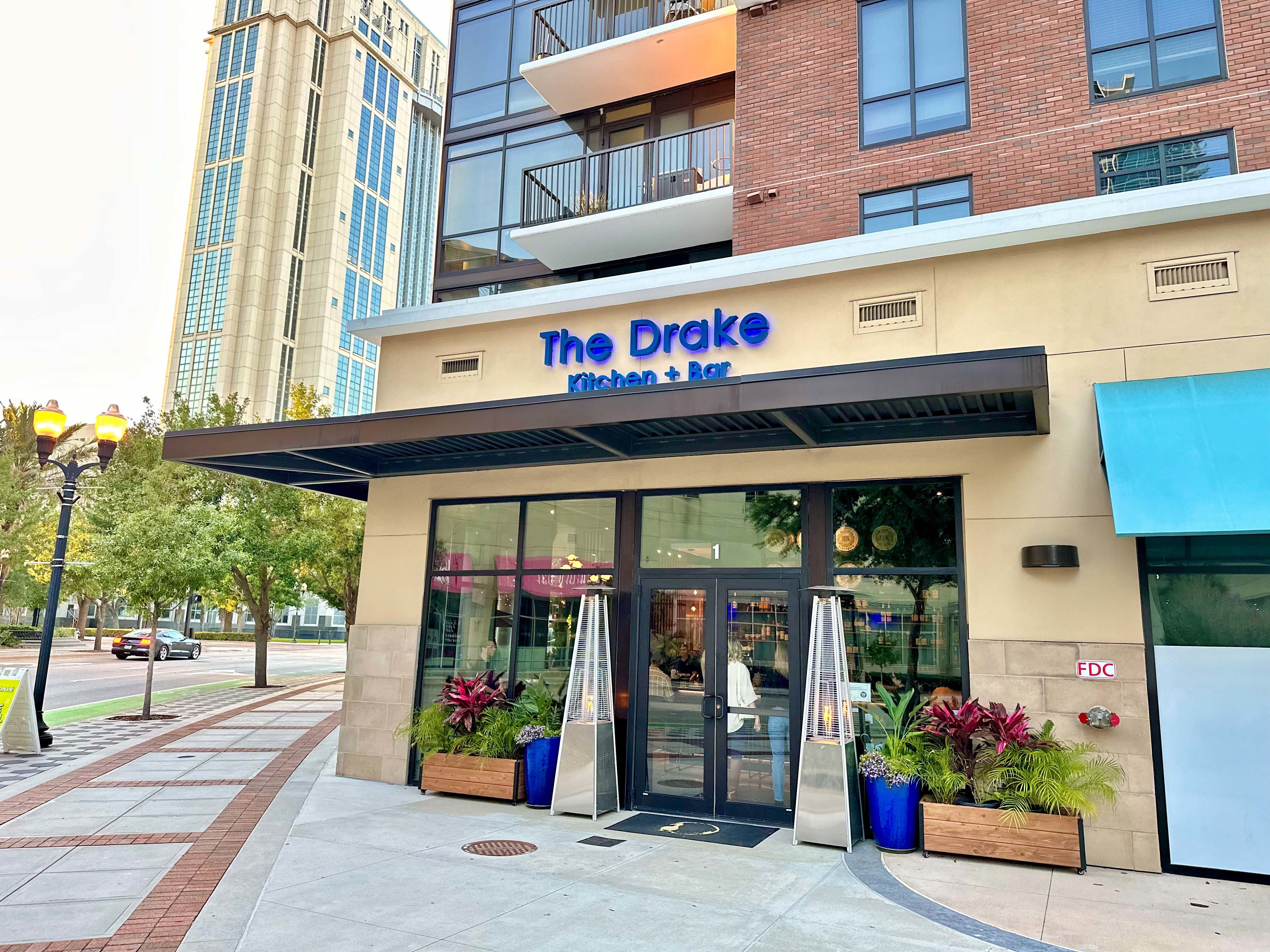 Front of The Drake restaurants with blue lettered sign and glass doors