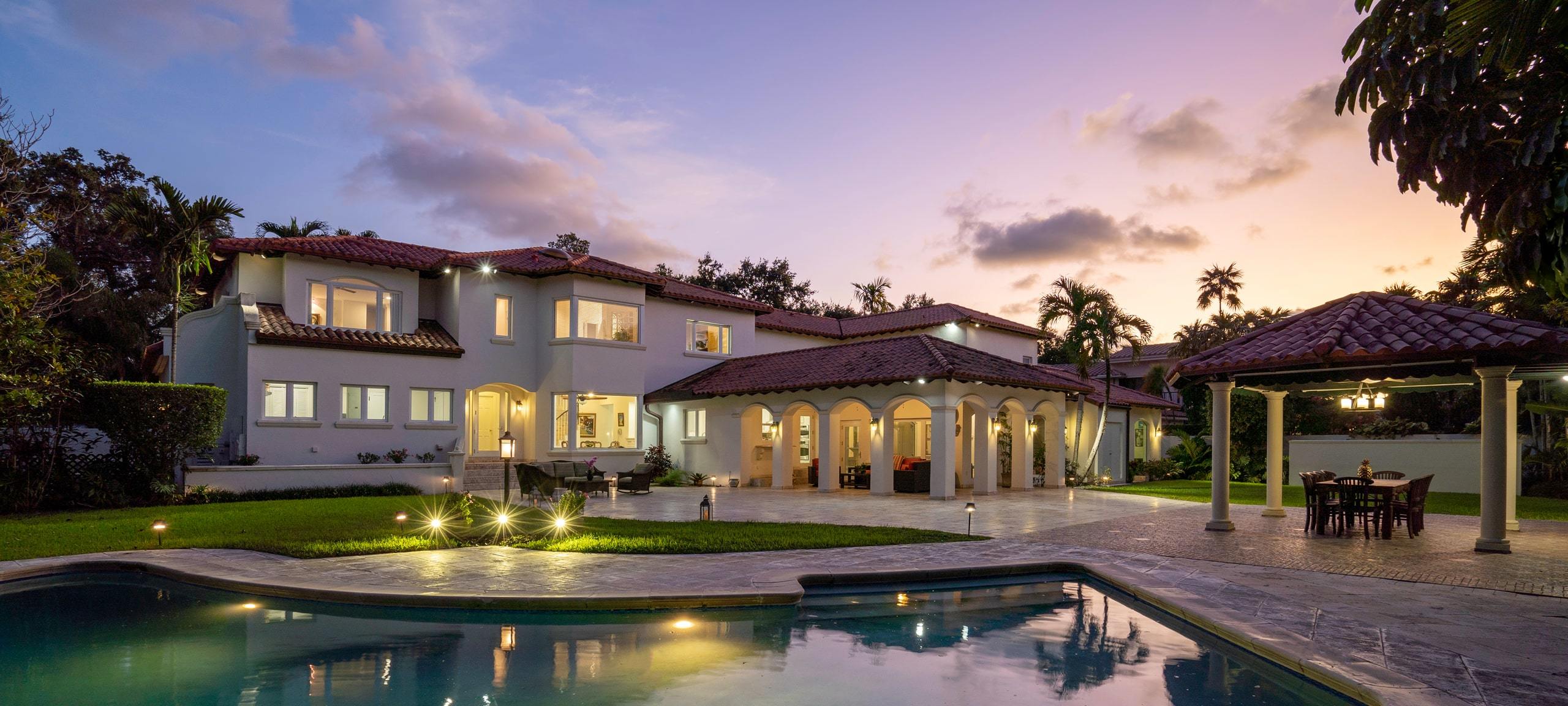 Luxury home from view of backyard pool during sunset