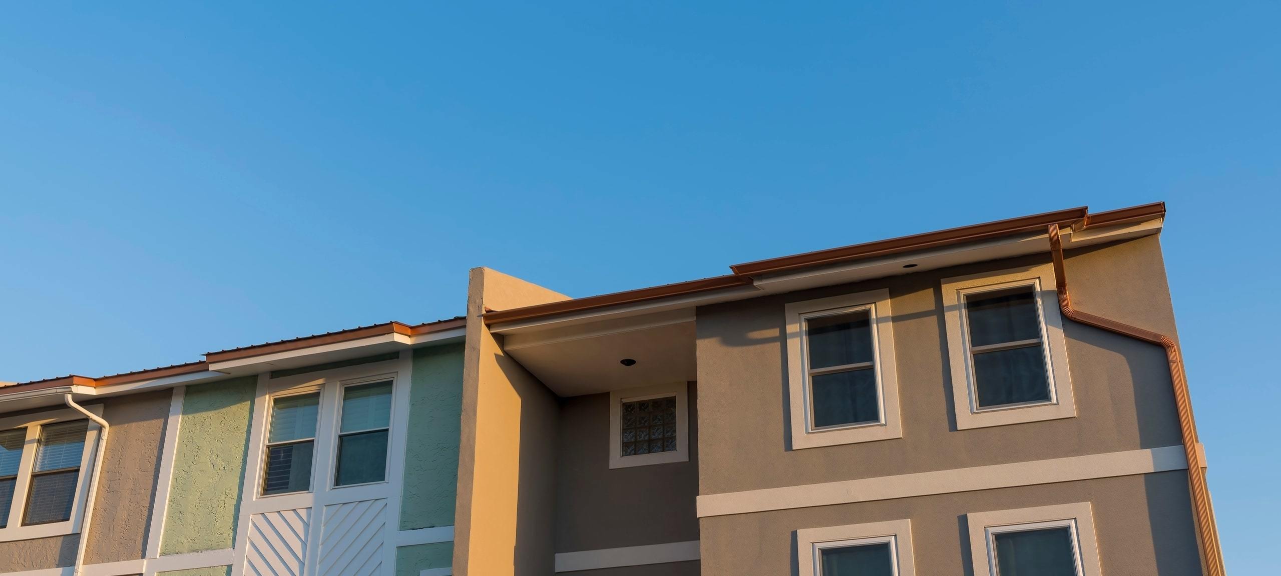 Upwards view of Mediterranean style townhomes against blue sky