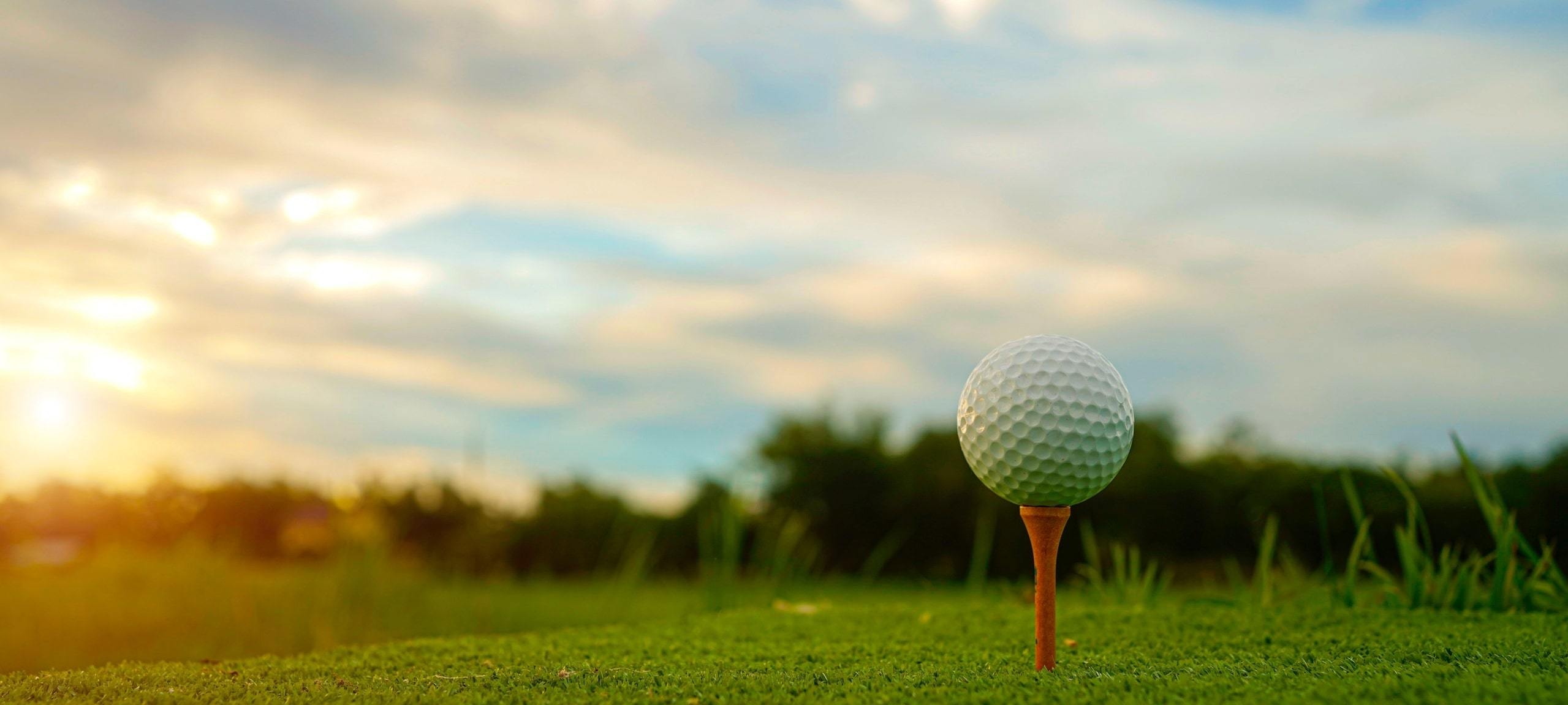 Up close shot of golf ball on course during sunset